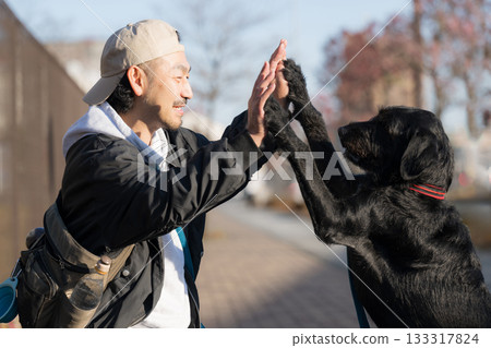 一個男人和他的寵物狗擊掌——這一幕展現了友誼和信任。 一個男人和他的寵物狗擊掌——這一幕展現了友誼和信任。 133317824