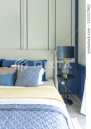 Interior of modern spacious master bedroom with big bed under a wall decoration and brown carpet. 133317902