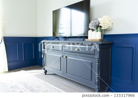 Elegant new TV cabinet made of veneer and solid walnut lumber near wall in blue wood wall. Elegant new TV cabinet made of veneer and solid walnut lumber near wall in blue wood wall. 133317966