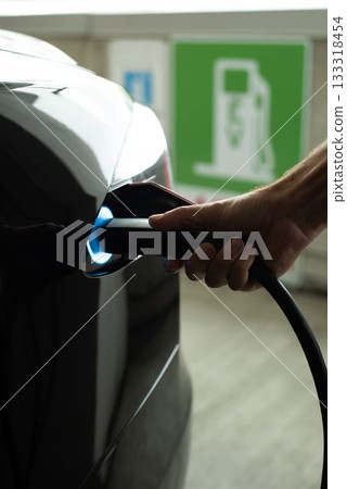 Man charging electric car at charging station Man charging electric car at charging station 133318454