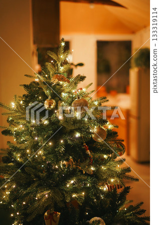 Close-up Detail of Golden Ornaments and Sparkling Lights on an Indoor Christmas Tree with Warm Orange Lighting Close-up Detail of Golden Ornaments and Sparkling Lights on an Indoor Christmas Tree with Warm Orange Lighting 133319114