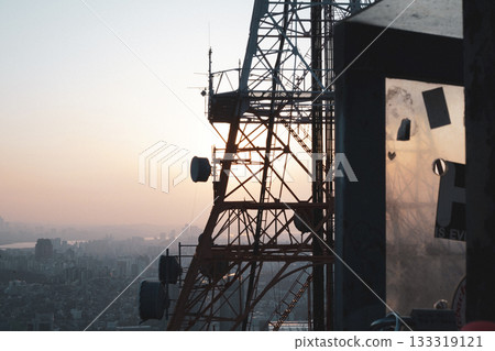 Communication Tower Structure Silhouette Against a City Sunset Communication Tower Structure Silhouette Against a City Sunset 133319121