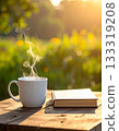 A steaming mug and a book on a natural wooden table 133319208