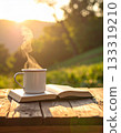 A steaming mug and a book on a natural wooden table 133319210