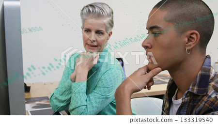 Leaning coworkers in green blouse and plaid shirt analyzing data on monitor at office with layouts 133319540
