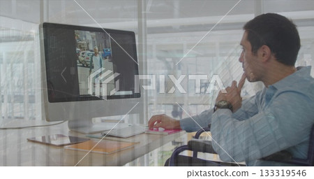 Wheelchair user wearing blue shirt viewing monitor screen at office desk, with smartphone Wheelchair user wearing blue shirt viewing monitor screen at office desk, with smartphone 133319546