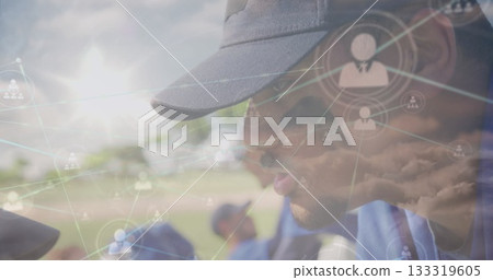 Leaning coach guiding kneeling team wearing blue jerseys on field with network overlays, copy space 133319605