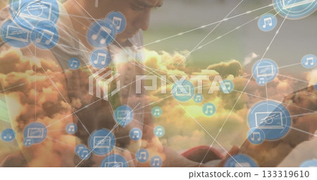 Leaning forward man in casual tee interacting with smartphone in cloud network, floating icons 133319610