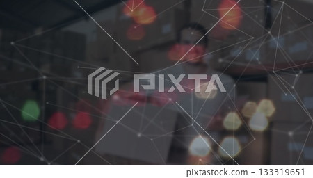 Holding box worker restocking shelves in warehouse, with digital network overlay and bokeh lights 133319651