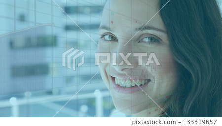 Smiling woman in office wear standing close to glass panel in office, with grid, financial charts 133319657