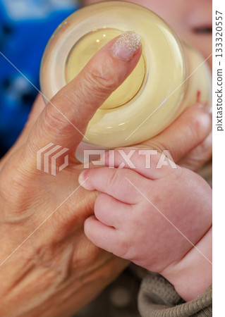 Baby's hand drinking milk from a baby bottle 133320557