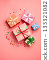 Top view of colorful gift boxes with decorative ribbons and scattered confetti on a soft pink background. Festive composition for celebrations, birthdays, holidays, and party invitations. 133321082