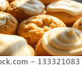 A delicious close-up shot of muffins with glossy icing, beautifully lit by warm natural light. 133321083