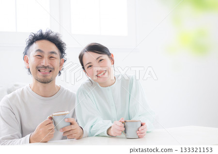 Relaxing scene of a smiling couple holding coffee cups Relaxing scene of a smiling couple holding coffee cups 133321153