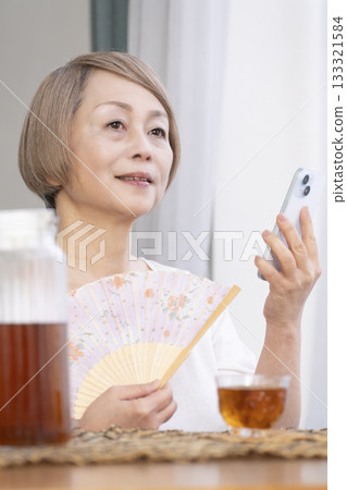 老婦人在客廳用風扇降溫 老婦人在客廳用風扇降溫 133321584