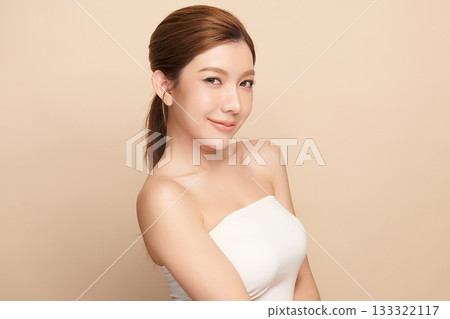 A beautiful young Asian woman with clean, fresh skin against a beige background. Skincare, facial treatment, cosmetology, beauty, and spa. An elegant portrait of an Asian woman. 133322117