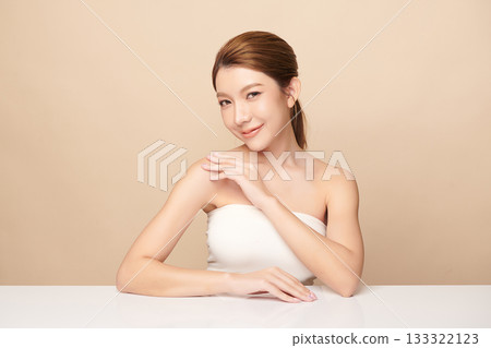 A beautiful young Asian woman with clean, fresh skin against a beige background. Skincare, facial treatment, cosmetology, beauty, and spa. An elegant portrait of an Asian woman. 133322123