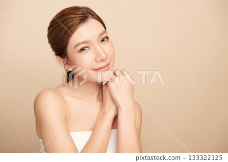 A beautiful young Asian woman with clean, fresh skin against a beige background. Skincare, facial treatment, cosmetology, beauty, and spa. An elegant portrait of an Asian woman. 133322125