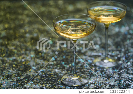 Two glasses of champagne on a table strewn with New Year's confetti, selective focus. Two glasses of champagne on a table strewn with New Year's confetti, selective focus. 133322244