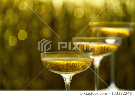 glasses of champagne on golden stylish background with golden bokeh circles with place for text. glasses of champagne on golden stylish background with golden bokeh circles with place for text. 133322246