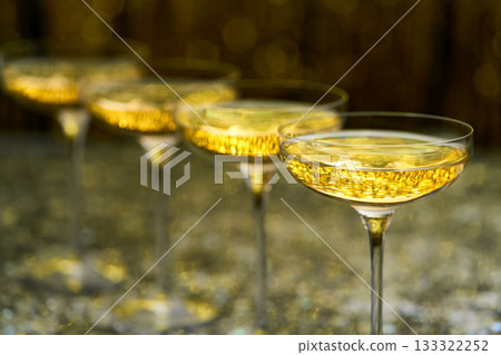 Many glasses of champagne in a line, selective focus. Lots of champagne in a  coupe glasses. 133322252
