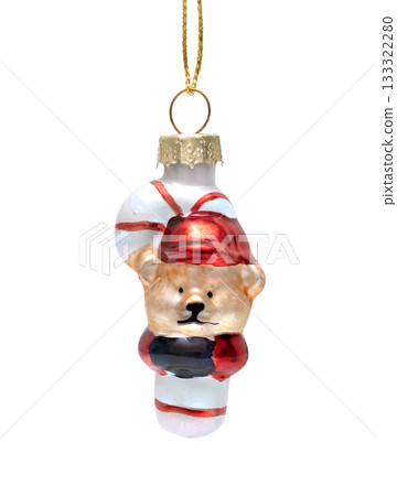 A cute glass Christmas ornament featuring a teddy bear wearing a red hat, hugging striped candy cane, isolated on white A cute glass Christmas ornament featuring a teddy bear wearing a red hat, hugging striped candy cane, isolated on white 133322280