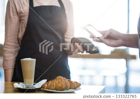 Man making payment through NFC technology in cafe 133322765