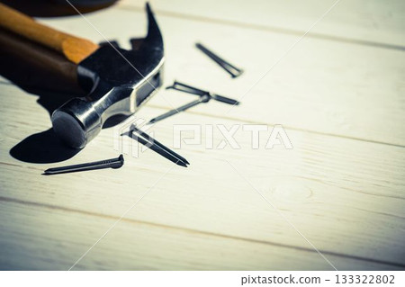 Claw hammer with wooden handle is resting near nails on painted boards, flat design, copy space Claw hammer with wooden handle is resting near nails on painted boards, flat design, copy space 133322802