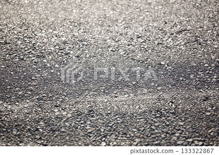 Close-up flat design showing rough asphalt pavement surface with stones reflecting subtle light 133322867