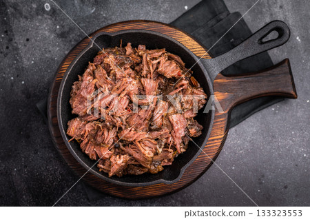 Traditional barbecue pulled beef, Slow cooked meat cooked in a smoker. black background. top view Traditional barbecue pulled beef, Slow cooked meat cooked in a smoker. black background. top view 133323553