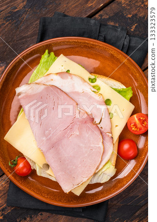 Prosciutto Cotto Ham and cheese sandwich, toast with sliced meat, cheese and salad. wooden background. top view 133323579