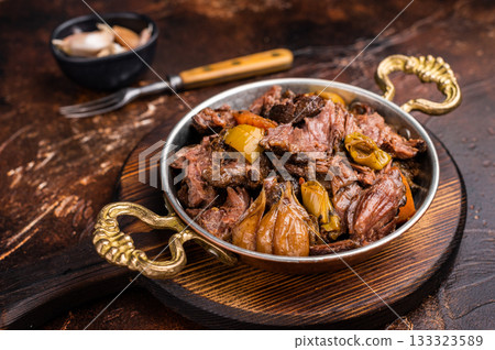 Slow cooked Beef Cheek, Braised meat with vegetables in a skillet. brown background. top view 133323589
