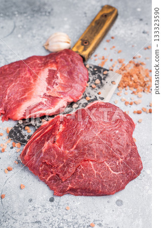 Raw beef cheeks on butcher meat cleaver. grey background. top view 133323590