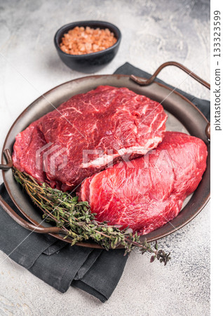 Uncooked beef cheeks, raw meat in steel tray. grey background. top view Uncooked beef cheeks, raw meat in steel tray. grey background. top view 133323599