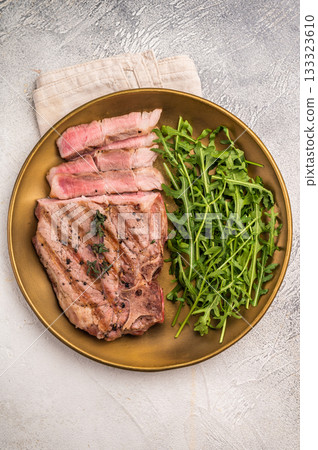 Roasted BBQ pork neck meat steak on plate with salad. grey background. top view Roasted BBQ pork neck meat steak on plate with salad. grey background. top view 133323610