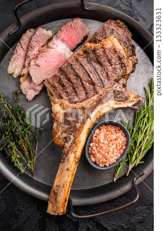 Roasted Tomahawk beef steak, roast dry aged rib eye with bone. black background. top view Roasted Tomahawk beef steak, roast dry aged rib eye with bone. black background. top view 133323631