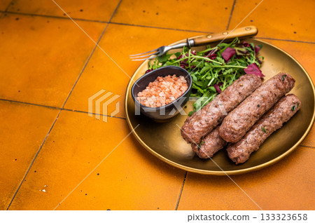 Grilled kofta or lula kebabs from mince lamb and beef meat on a plate with salad. brown background. top view 133323658