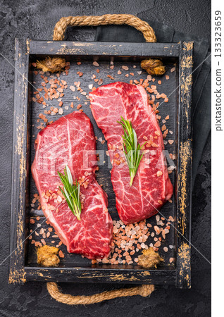 Raw Top blade steak, shoulder beef meat in wooden tray. black background. top view 133323659