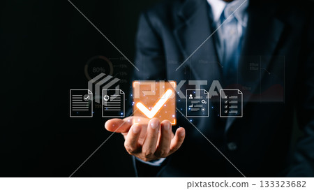 A businessman professional holds a glowing digital certificate document icons, a large checkmark symbolizing digital approve processes, focusing on business quality assurance and data management. 133323682