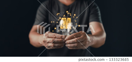 A person holds a glowing lightbulb with digital connections and the text AI inside, symbolizing idea, innovation, and creative technology powered by artificial intelligence and neural networks. A person holds a glowing lightbulb with digital connections and the text AI inside, symbolizing idea, innovation, and creative technology powered by artificial intelligence and neural networks. 133323685