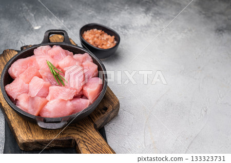 Raw turkey fillet pieces, diced poultry breast meat in a skillet. grey background. top view 133323731