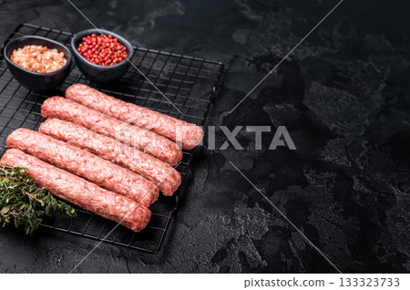 Uncooked Raw Cevapcici Sausage, fresh Cevapi from mince beef and pork meat on a rack. black background. top view Uncooked Raw Cevapcici Sausage, fresh Cevapi from mince beef and pork meat on a rack. black background. top view 133323733