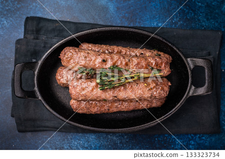 Grilled Cevapcici Sausage, roasted Cevapi from mince beef and pork meat in a skillet. blue background. top view Grilled Cevapcici Sausage, roasted Cevapi from mince beef and pork meat in a skillet. blue background. top view 133323734