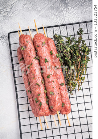 Raw kofta or lula kebabs skewers from mince lamb and beef meat on Skewer. grey background. top view Raw kofta or lula kebabs skewers from mince lamb and beef meat on Skewer. grey background. top view 133323754