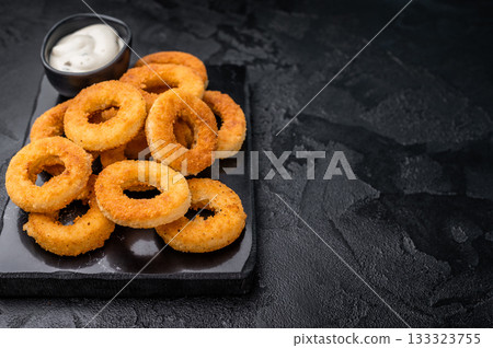 Deep fried squid rings with breading, calamari fastfood snack. black background. top view Deep fried squid rings with breading, calamari fastfood snack. black background. top view 133323755