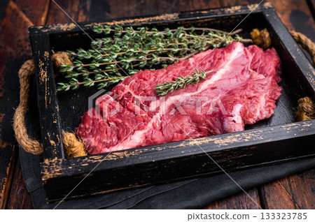Uncooked hanging tender beef steak, Hanger steak in wooden tray with herbs. wooden background. top view 133323785