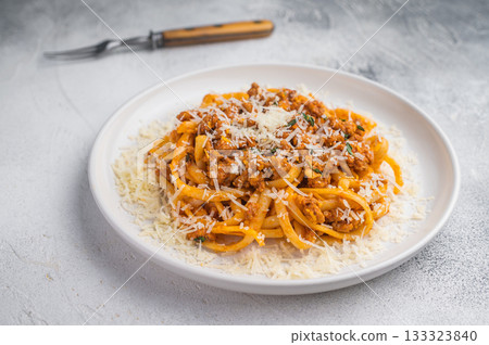 Delicious pasta bolognese sprinkled with parmesan on a textured gray backdrop, bright clean flat lay food photograph. Delicious pasta bolognese sprinkled with parmesan on a textured gray backdrop, bright clean flat lay food photograph. 133323840