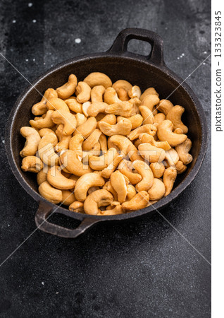 Closeup of cashews in a cast iron dish over a dark artistic background creating a bold natural scene ideal for gourmet and healthy eating visuals 133323845
