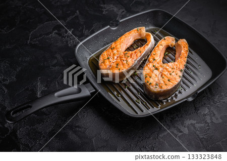 The salmon steaks are seared on a hot grill surface, where oil and herbs enhance the aroma and highlight the intense cooking method. The salmon steaks are seared on a hot grill surface, where oil and herbs enhance the aroma and highlight the intense cooking method. 133323848