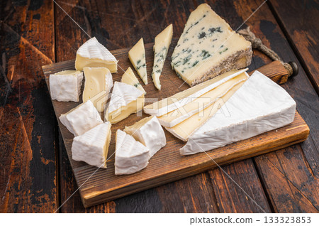Selection of creamy Brie soft Camembert and blue Roquefort displayed on a textured wooden board for an artisanal gourmet look. 133323853